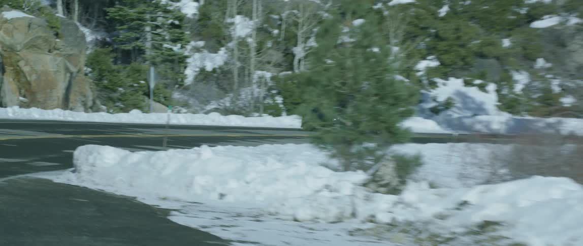 A car drives on a road surrounded by snow