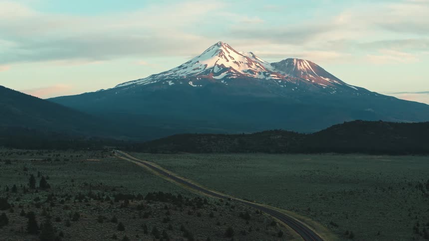 The top of a snowy mountain rises above a valley