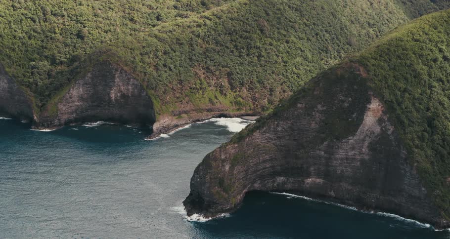 Ocean waves splash against the curved rocky shore and inlet
