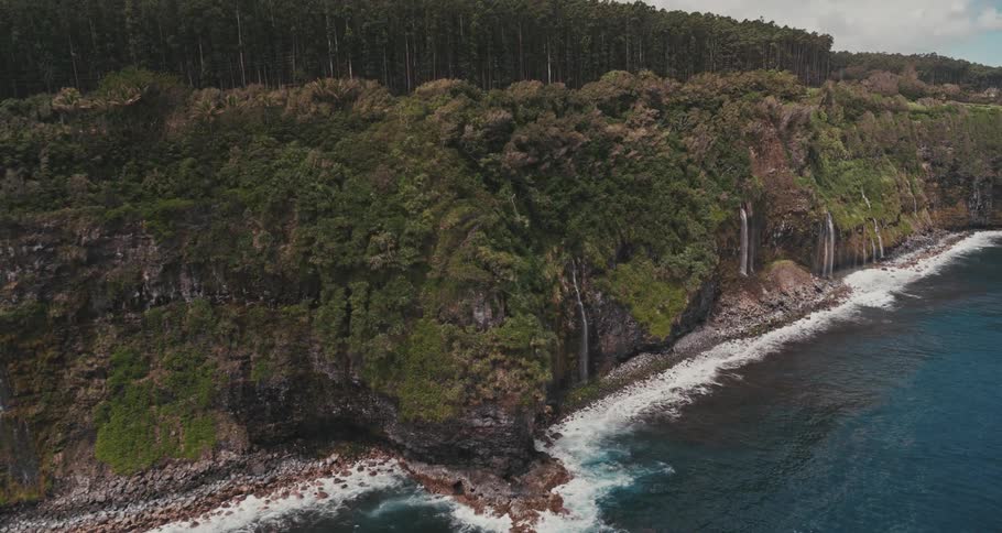 Aerial view of waterfalls flowing from cliffs near the beach