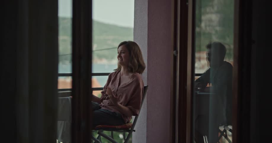 A woman is sitting at a table talking and moving her arms as she speaks