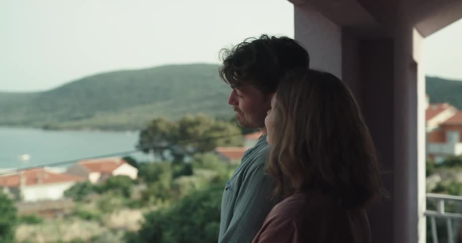 Husband and wife are standing close to each other on a balcony