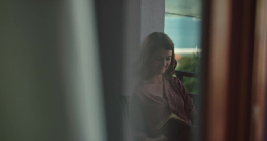 Woman relaxes reading a book in an apartment balcony near the ocean