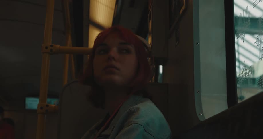 A woman sitting on a train stands as it comes to a stop and moves to get off at the terminal