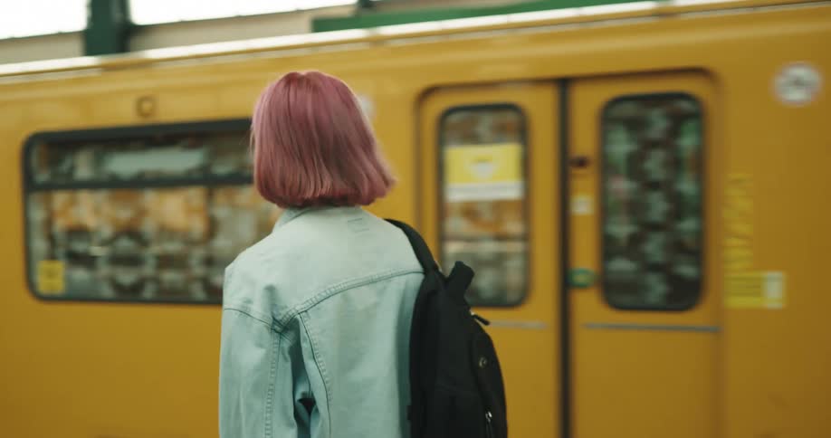 A woman walks up to a train car as it comes to a stop