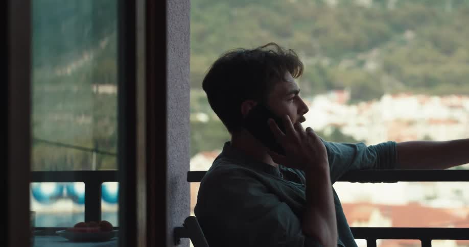 A man is on a balcony talking on the phone