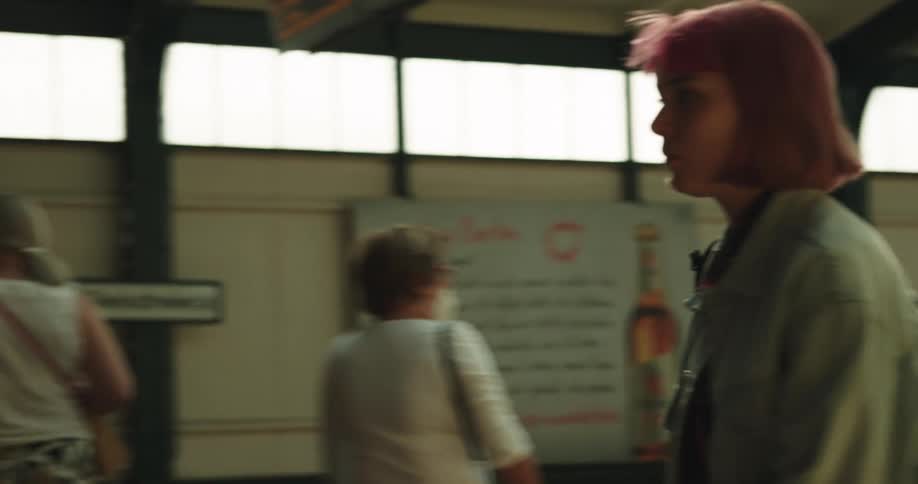 Young woman with short red hair gets off a train to exit the station