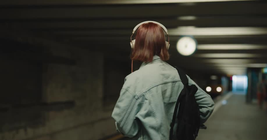 A woman standing at a train station waiting for a train