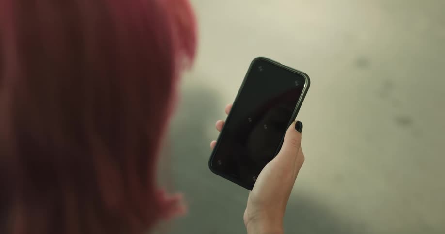A womans hand holding a phone using her thumb to scroll and tap the screen