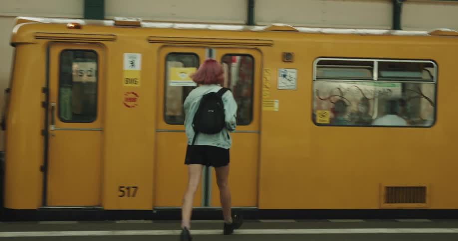 A woman runs up the stairs and enters the train