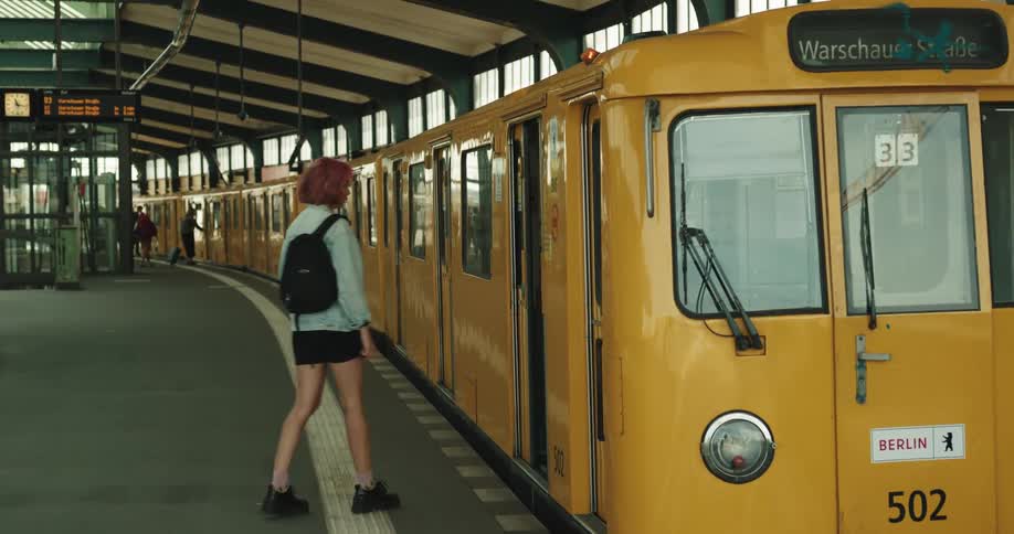 Woman watches train arrive before waiting for passengers to exit then boarding