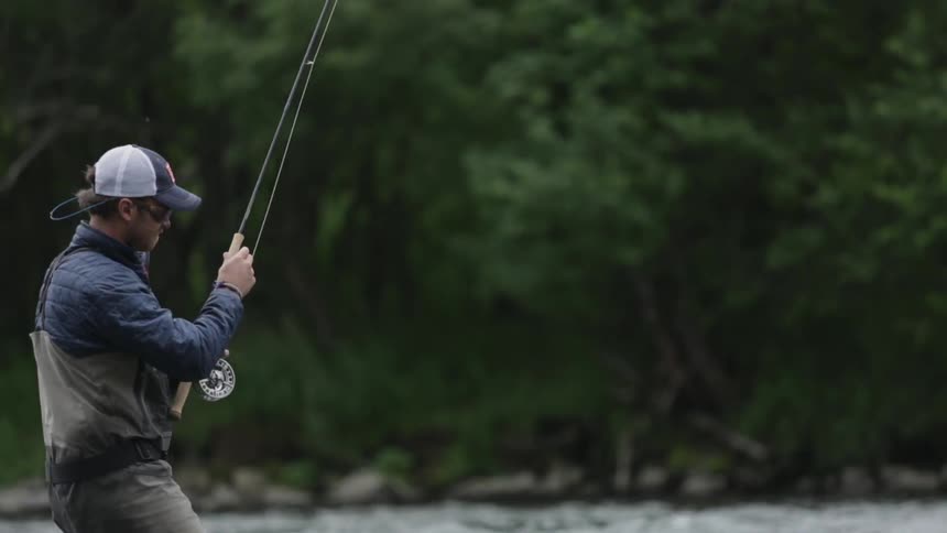 A fisherman casting from the middle of a stream