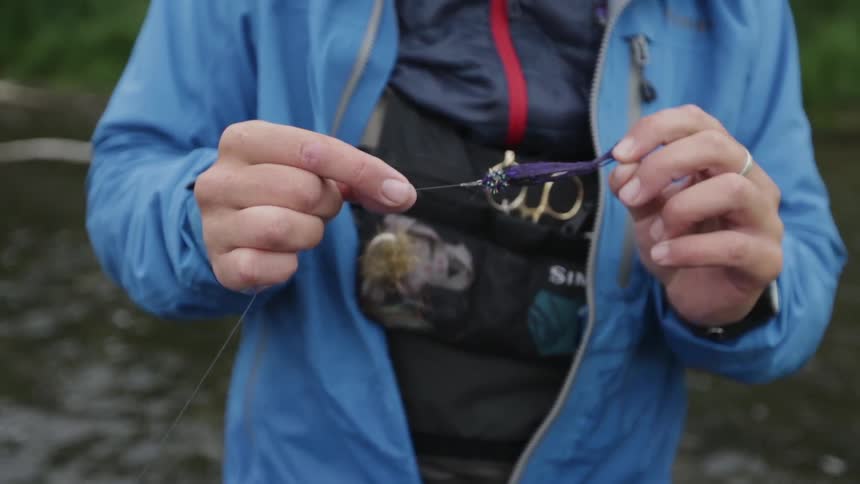 A man holds and examines a fishing lure