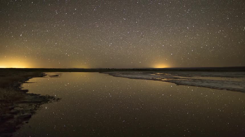 Timelapse of lake with starry night sky reflection in remote location