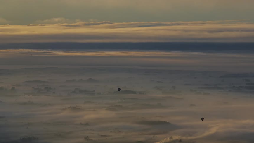 Timelapse of hot air balloons taking off in the sky during sunrise.