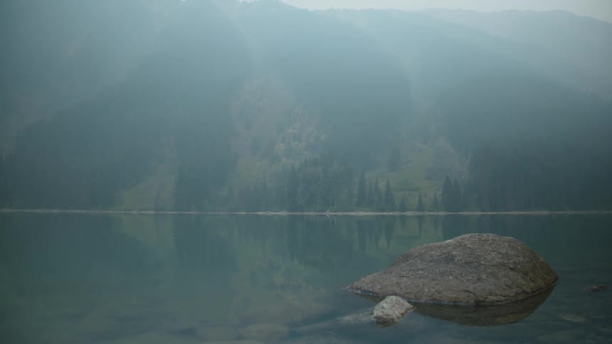 wildfire smoke over lake with mountains in the distance