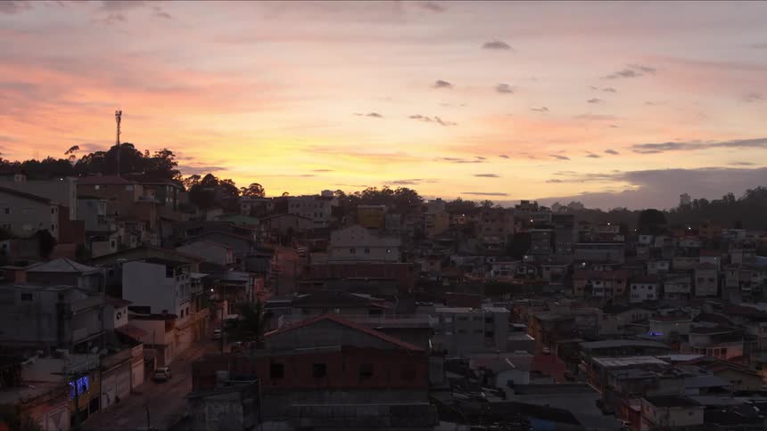 A peripheral neighborhood with houses, streets and vehicles in early morning, magic hour sky and clouds in the background