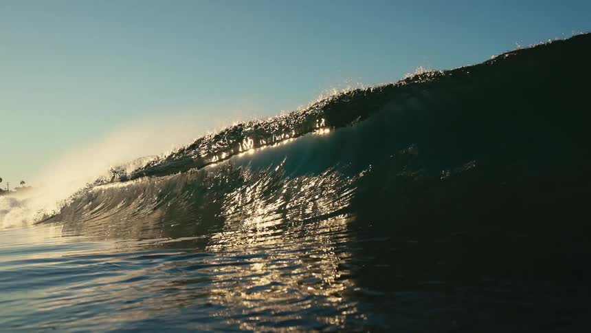 A huge wave rolls overhead as it glistens in the sunlight