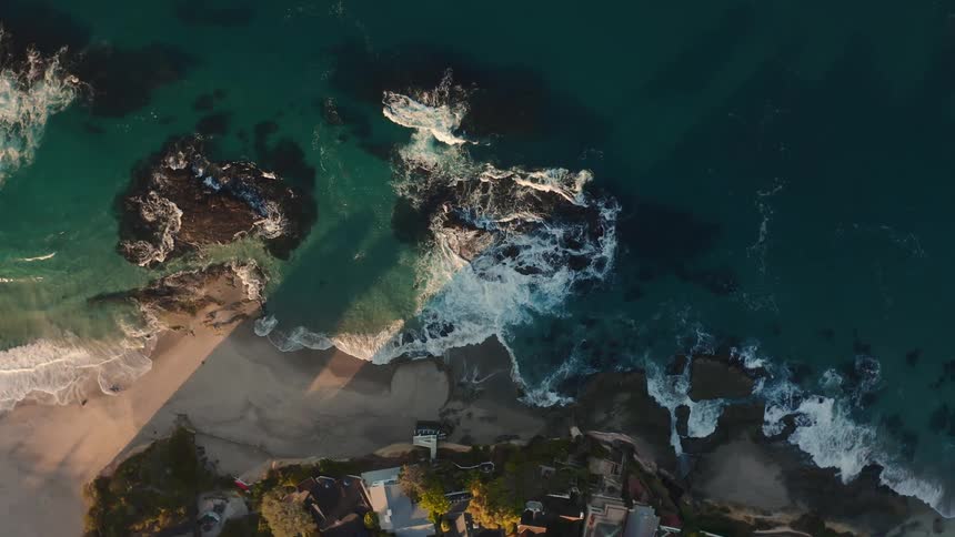 Houses and trees close to the beach with water and waves