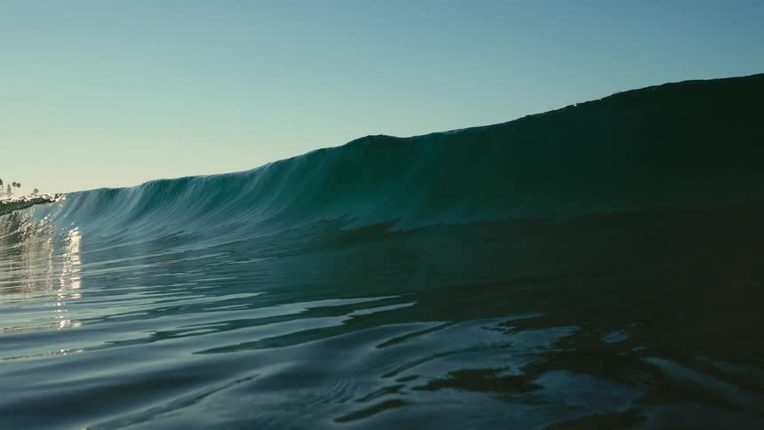 Close view of an ocean wave developing and curling over in a coastal region in the evening