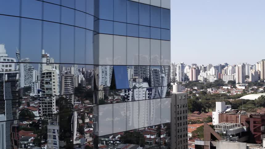 A downtown skyline reflects off a mirrored skyscraper