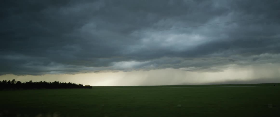 A large storm is pouring rain in the distance