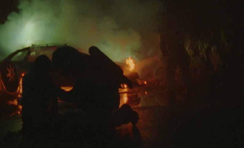 A firefighter puts an oxygen mask on a small victim as other fight the flaming car fires