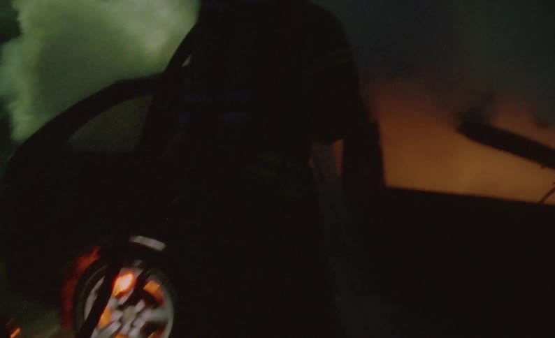 A firefighter spraying off a car on fire