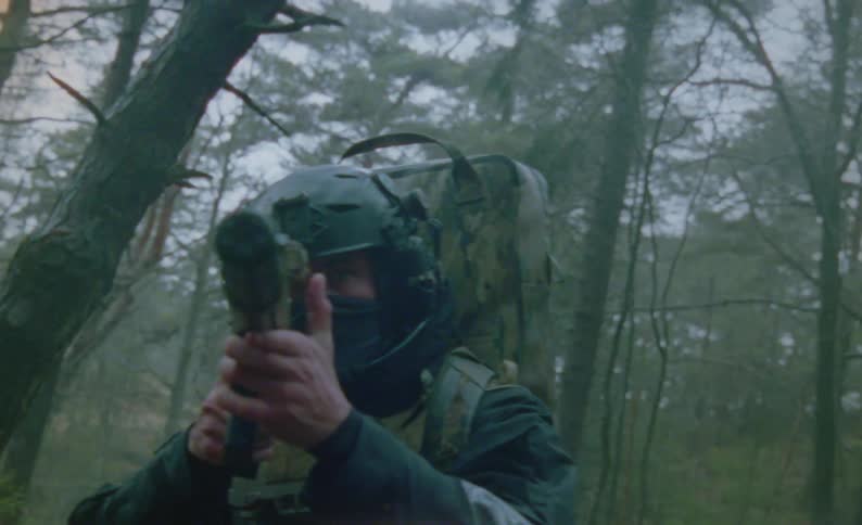 A soldier walking through a forest in the fall