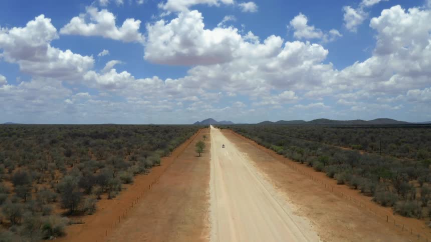 A car is racing on the dirt road alone during the day