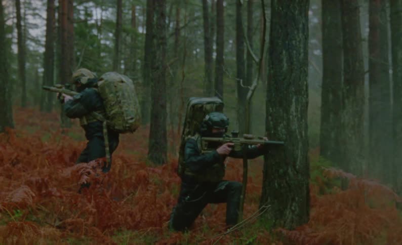 Two men in a forest with rifles with the sky and clouds in the background