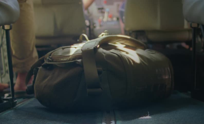 A backpack lies on the floor of a large vehicle as it travels during the day