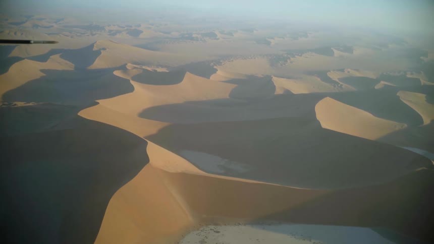 A desert with sandy dunes with the sky and clouds in the background