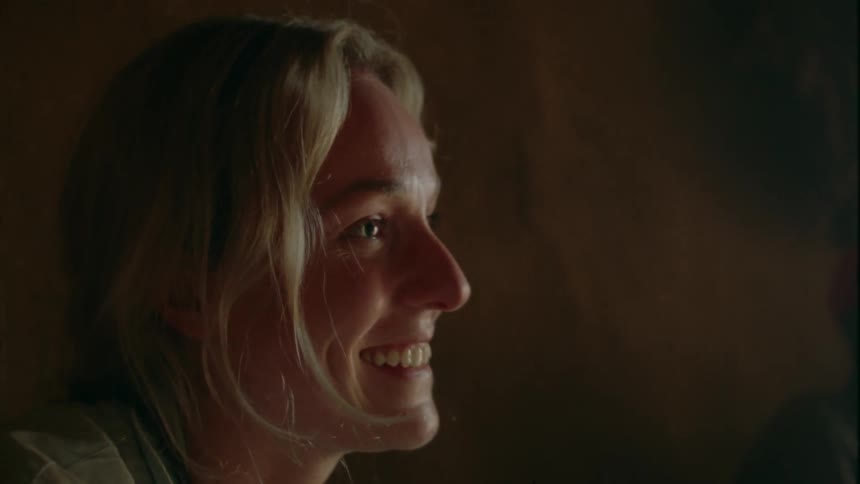 A woman smiles as she talks while sitting indoors