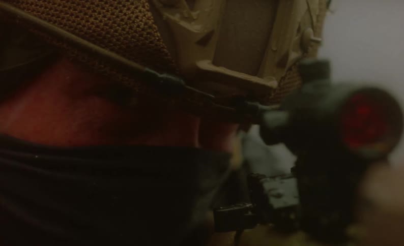 A soldier aims a firearm with a laser scope on a snowy day