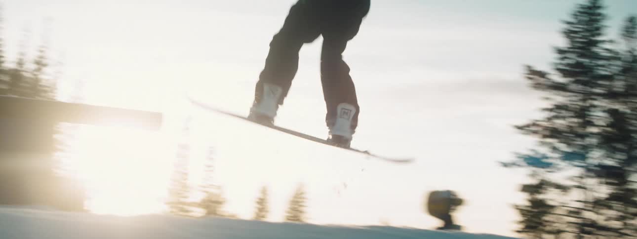 A person with a helmet and goggles snowboarding with trees the sky and clouds in the background