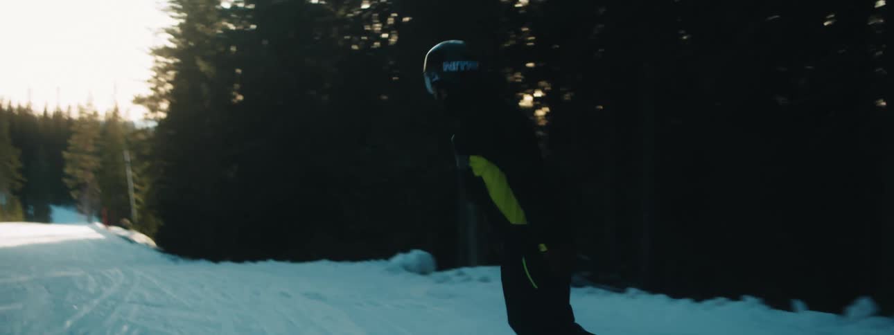 A snowboarder weaves back and forth while going down a mountain