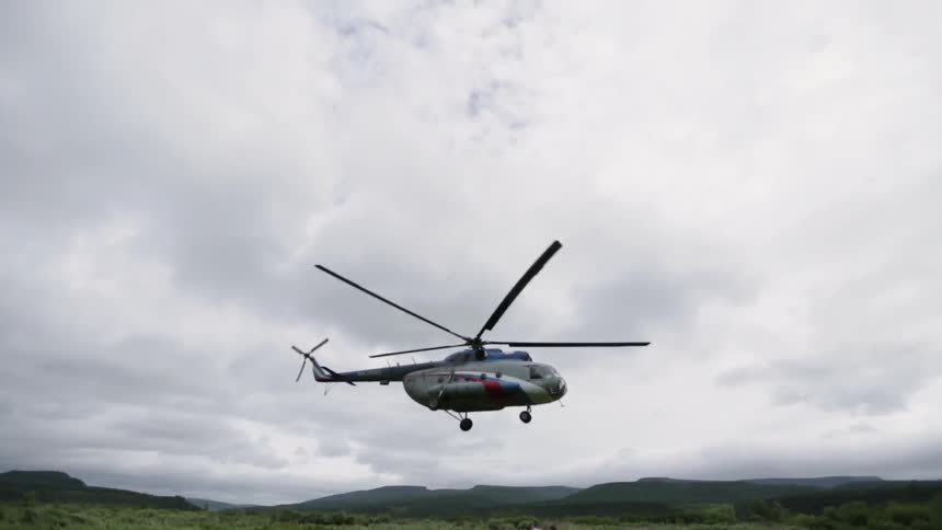 A helicopter lifts off into a cloudy sky