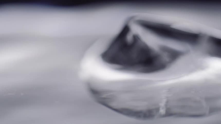 Ice cube floats across surface of water both reflecting light