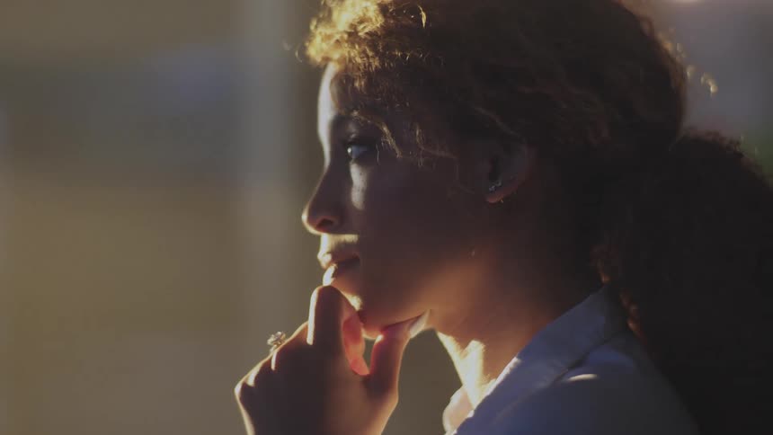 Close up of the face of a woman with her fingers over the mouth thinking at evening