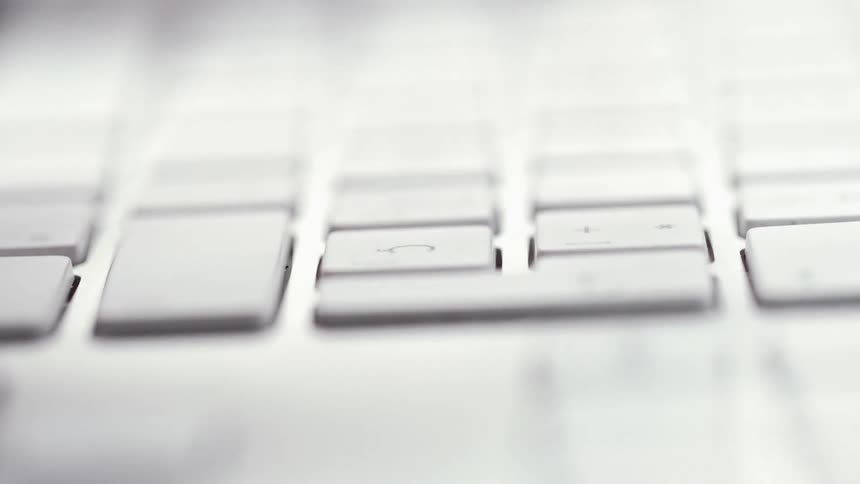 A woman types rapidly on a laptop