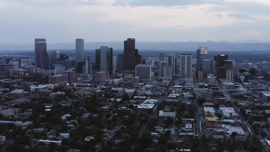 An aerial view of the tower block of a city and surrounding buildings at dusk