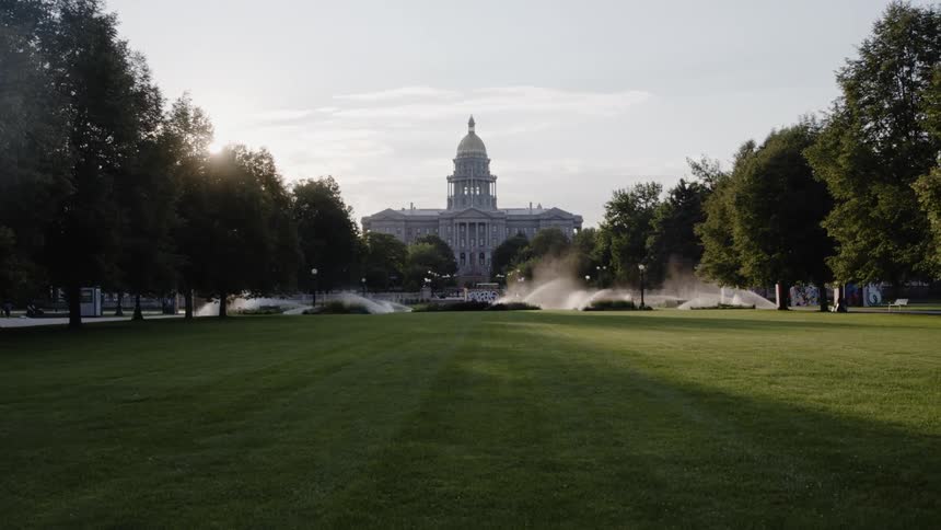 Water fountains spray in front of a government building with a large dome on top