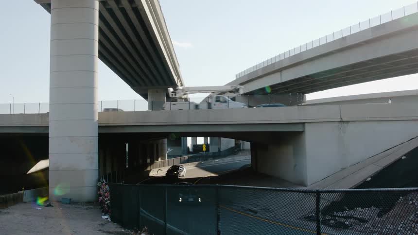 Vehicles driving on the highway with overpasses with the sky and clouds in the background