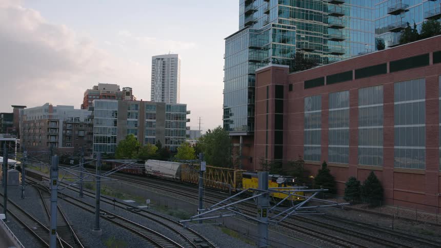 A freight train is slowly moving into a train yard in a city during the day