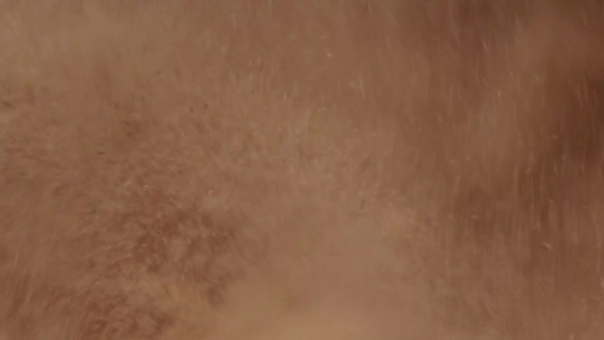 Pale pinkish liquid churns creating foam and spray
