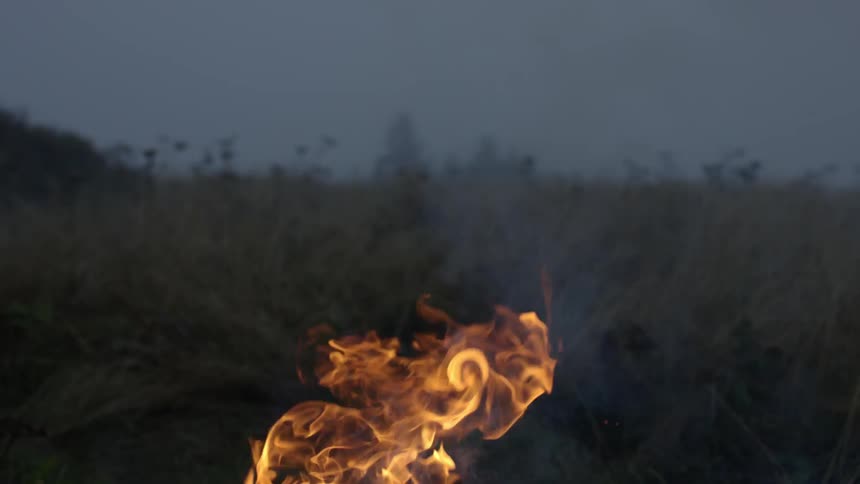 A fire rises in the sky by a hill
