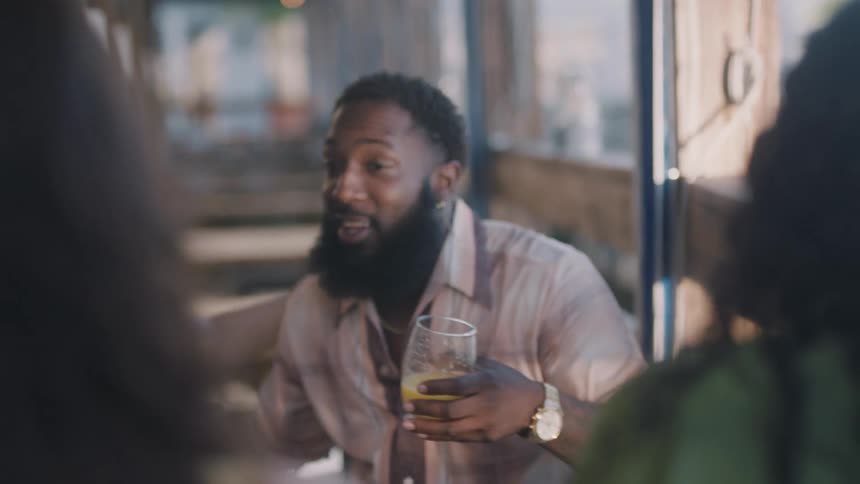 A man sits down talking with a drink