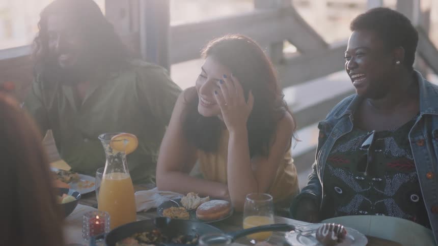 A group of friends laugh over mimosas and brunch on a patio