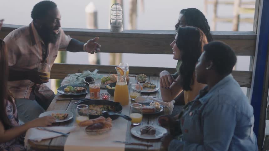 Two men and three women sitting at a table with food and drinks
